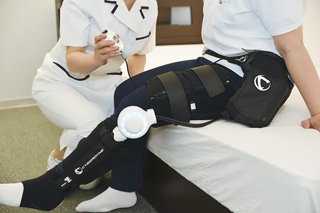 ベッドに腰かけ、膝にHALを装着して脚を伸ばす様子